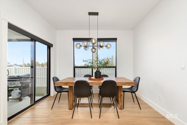 dining room with light hardwood / wood-style floors and a notable chandelier