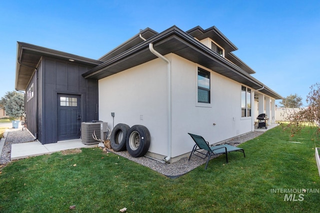 view of side of property with central AC and a lawn