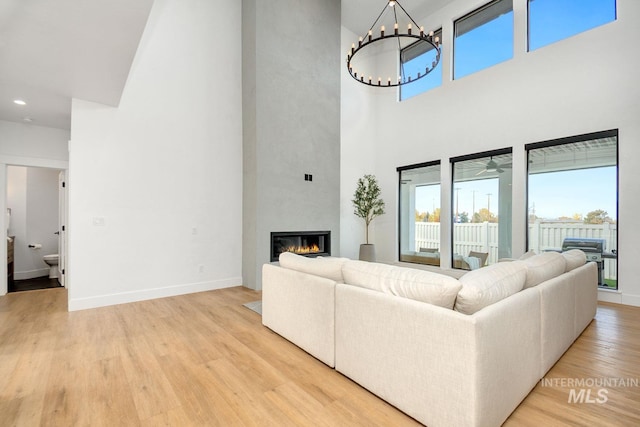 living room with ceiling fan, light hardwood / wood-style floors, and a high ceiling