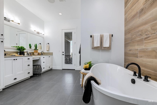 full bathroom with tile patterned floors, double vanity, a freestanding tub, and recessed lighting