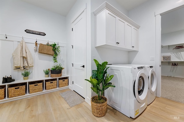 laundry room featuring washing machine and clothes dryer, cabinet space, and light wood-style floors