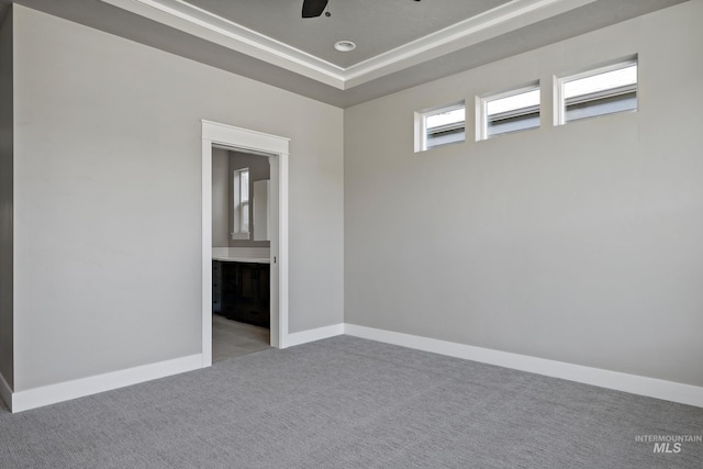 unfurnished room with baseboards, a raised ceiling, a ceiling fan, and light colored carpet