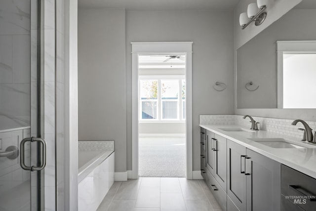 bathroom featuring double vanity, a stall shower, a sink, and tiled bath