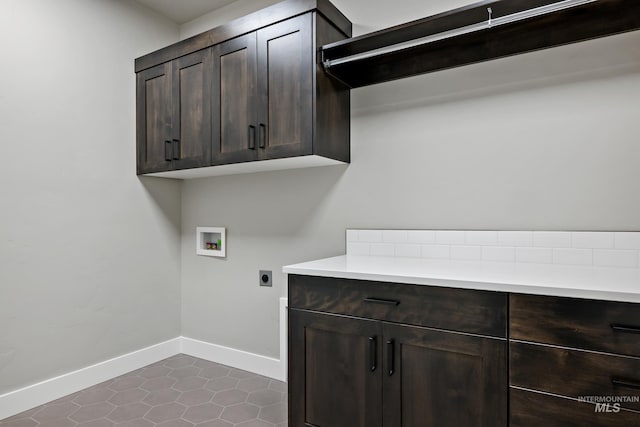 laundry room featuring washer hookup, cabinet space, hookup for an electric dryer, dark tile patterned floors, and baseboards