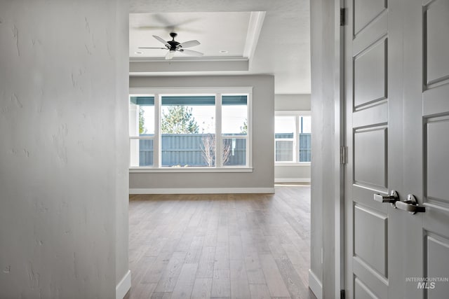 hallway with baseboards, a raised ceiling, wood finished floors, and ornamental molding