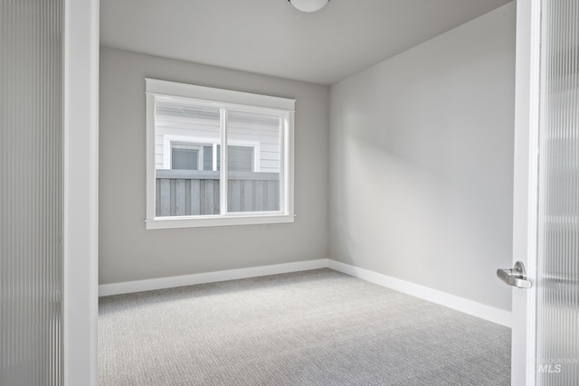 unfurnished room featuring carpet and baseboards