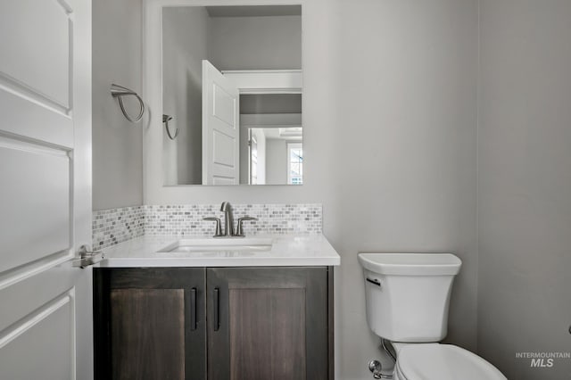 half bath featuring backsplash, toilet, and vanity