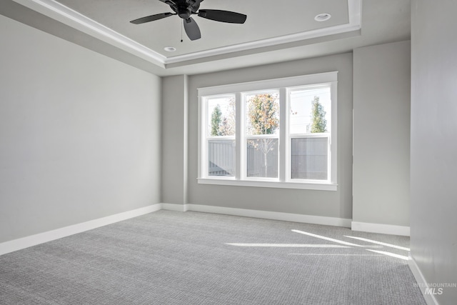 unfurnished room with ceiling fan, carpet flooring, a raised ceiling, and baseboards