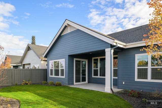 back of property featuring a patio area, roof with shingles, fence, and a yard