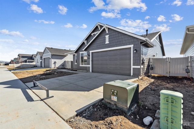 view of side of property featuring fence, concrete driveway, an attached garage, and a gate