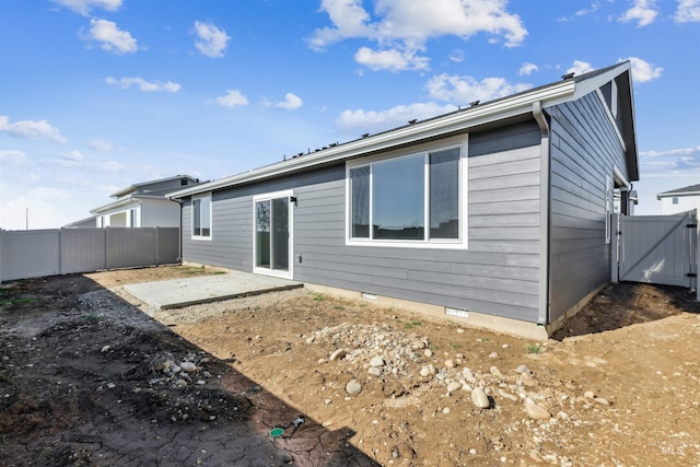 back of property featuring a gate, crawl space, fence, and a patio area