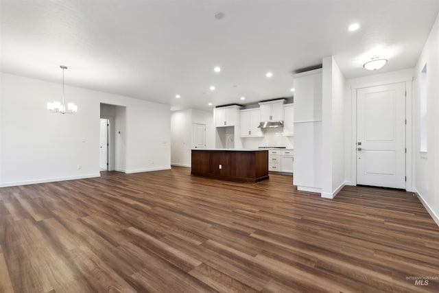 unfurnished living room featuring recessed lighting, a notable chandelier, and dark wood finished floors