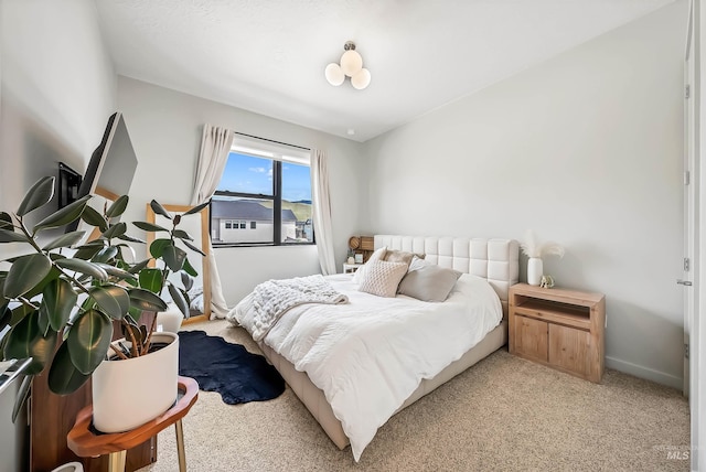 bedroom with light colored carpet and baseboards