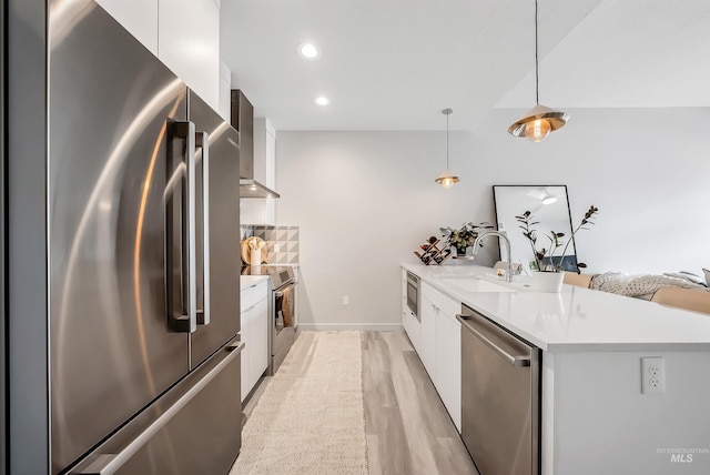 kitchen featuring light countertops, appliances with stainless steel finishes, a peninsula, modern cabinets, and a sink