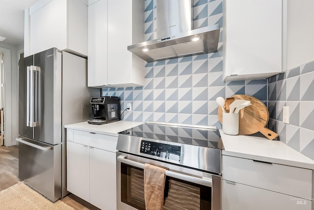 kitchen with ventilation hood, light countertops, white cabinets, appliances with stainless steel finishes, and backsplash