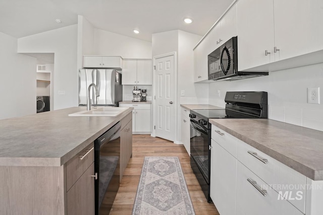 12740 Abbeygate Dr, Nampa, ID 83651 - kitchen featuring black appliances, light wood-style flooring, washer / dryer, white cabinets, and vaulted ceiling