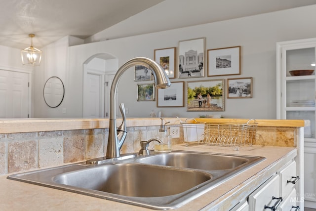 kitchen featuring decorative backsplash, sink, decorative light fixtures, white cabinets, and lofted ceiling