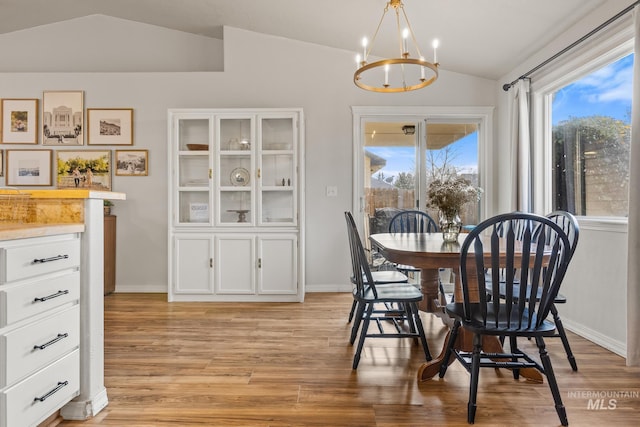 dining area featuring light hardwood / wood-style floors, a notable chandelier, and vaulted ceiling