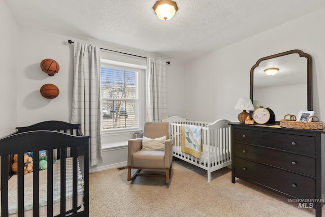 carpeted bedroom featuring a nursery area and a textured ceiling