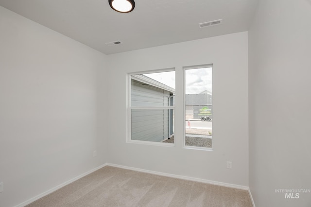 empty room featuring baseboards, visible vents, and light colored carpet