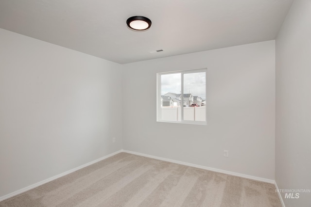 unfurnished room featuring visible vents, baseboards, and light colored carpet