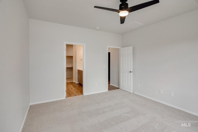 unfurnished bedroom with baseboards, ensuite bathroom, visible vents, and light colored carpet