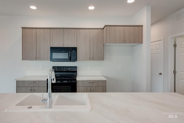 kitchen with black appliances, light brown cabinets, light countertops, and a sink