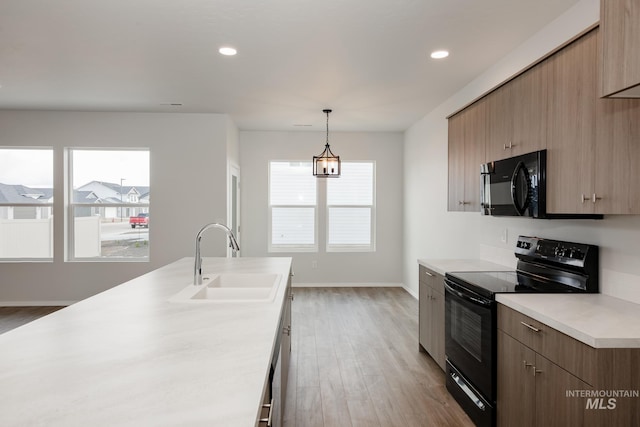 kitchen with a sink, black appliances, modern cabinets, and light countertops