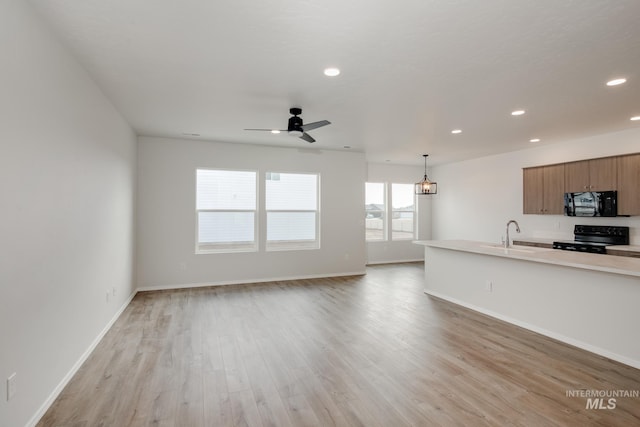 interior space with light wood-style floors, baseboards, a sink, and recessed lighting