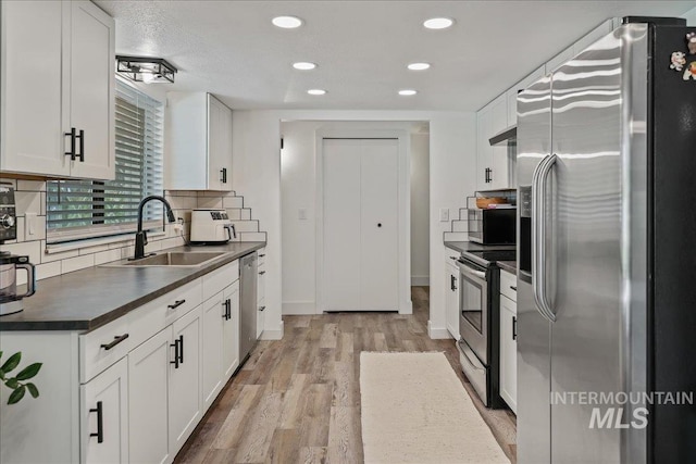 15103 Castle Way, Caldwell, ID 83607 - kitchen featuring stainless steel appliances, a sink, dark countertops, light wood finished floors, and white cabinets