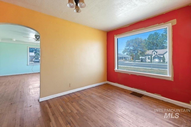 359 Falls Ave W, Twin Falls, ID 83301 - spare room with wood-type flooring, arched walkways, a ceiling fan, baseboards, and a textured ceiling