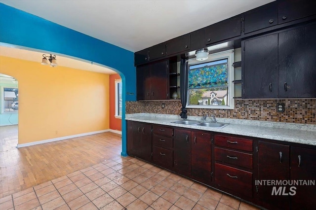 359 Falls Ave W, Twin Falls, ID 83301 - kitchen featuring open shelves, arched walkways, a sink, decorative backsplash, and baseboards