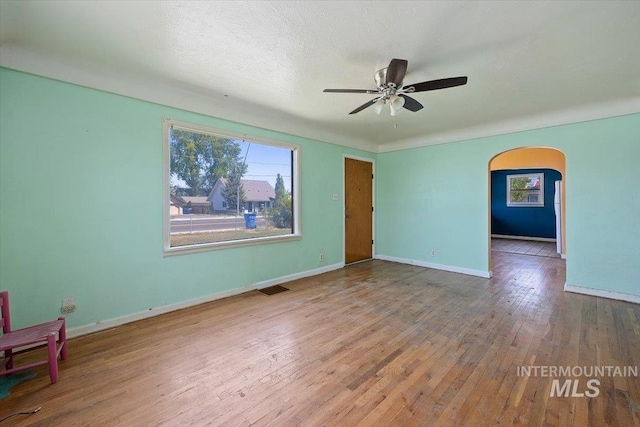 359 Falls Ave W, Twin Falls, ID 83301 - unfurnished room featuring arched walkways, a ceiling fan, wood finished floors, and baseboards