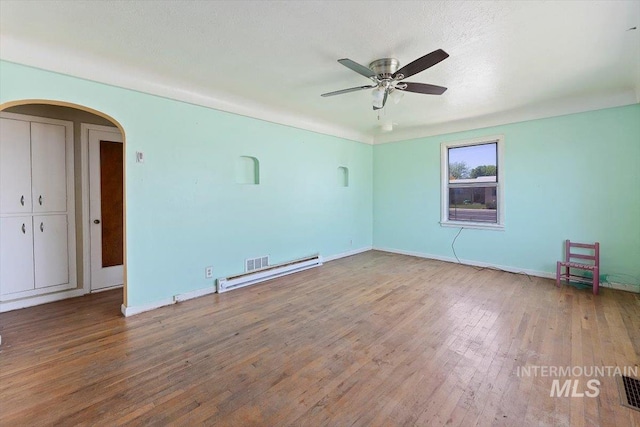 359 Falls Ave W, Twin Falls, ID 83301 - empty room with arched walkways, a ceiling fan, wood finished floors, a baseboard radiator, and baseboards