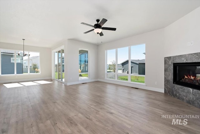 6150 S Binky Ave, Meridian, ID 83642 - unfurnished living room with wood finished floors, baseboards, a premium fireplace, ceiling fan, and a chandelier