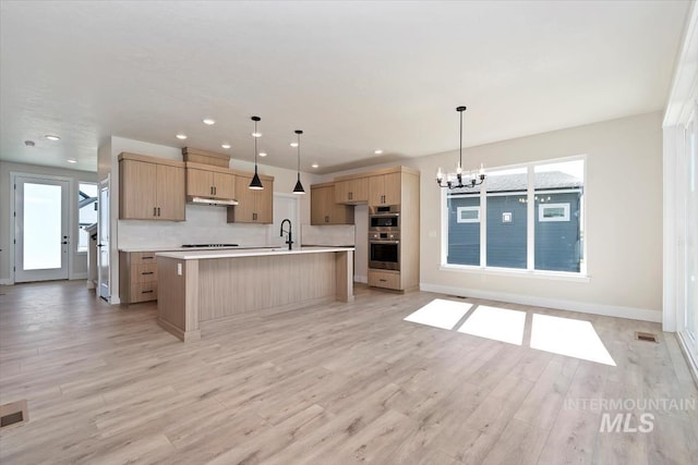 6150 S Binky Ave, Meridian, ID 83642 - kitchen with light brown cabinets, a chandelier, light countertops, under cabinet range hood, and an island with sink