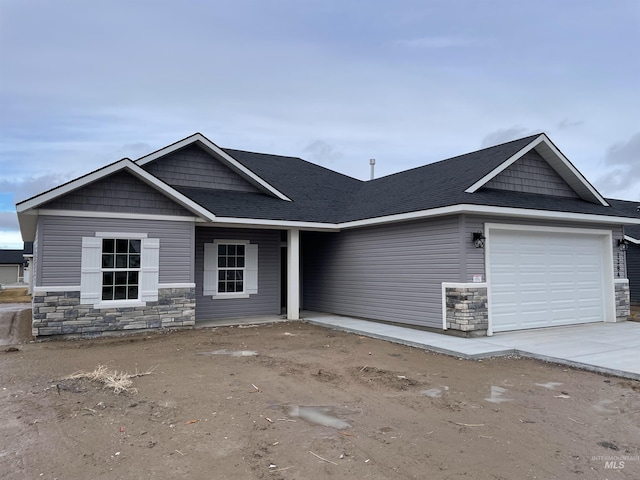 view of front of property featuring a garage, stone siding, and driveway