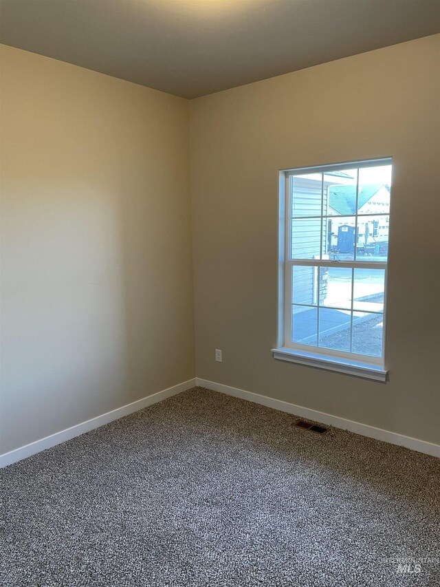 carpeted spare room featuring baseboards and visible vents