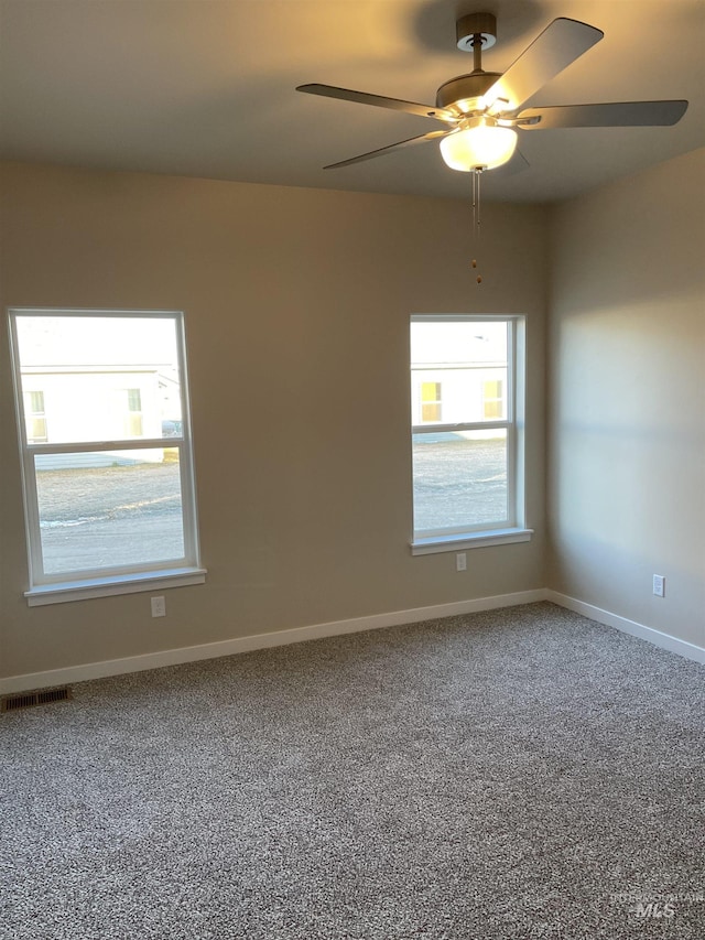 unfurnished room with visible vents, baseboards, carpet, and a ceiling fan
