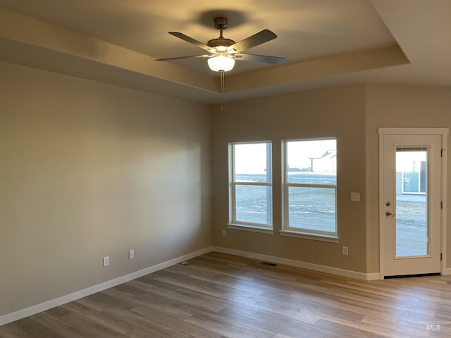 unfurnished room featuring ceiling fan, baseboards, a raised ceiling, and wood finished floors