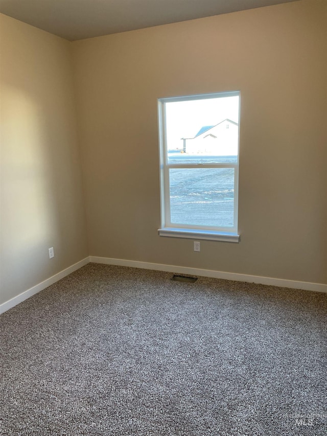 carpeted spare room with visible vents and baseboards