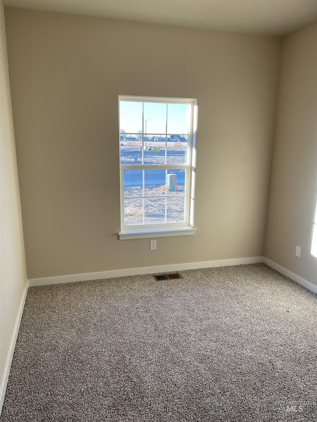 carpeted spare room with visible vents and baseboards