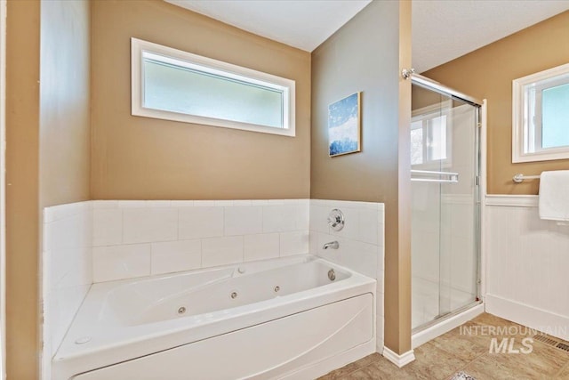 bathroom featuring a whirlpool tub, wainscoting, a shower stall, and tile patterned floors