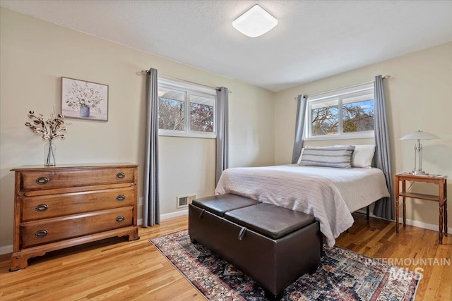 bedroom with light wood-style floors, visible vents, and baseboards