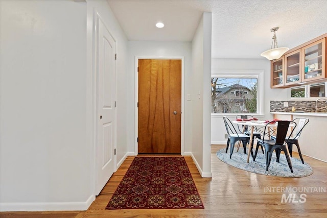 doorway to outside featuring light wood finished floors, baseboards, and recessed lighting