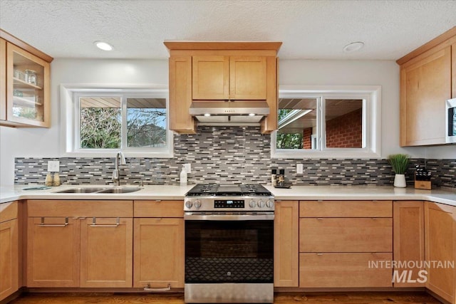 kitchen featuring gas stove, light countertops, a sink, and under cabinet range hood