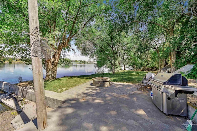 view of patio / terrace with a fire pit, grilling area, and a water view