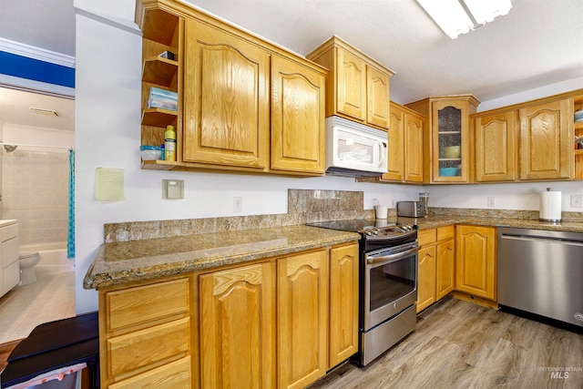 kitchen featuring light hardwood / wood-style flooring, light stone counters, and appliances with stainless steel finishes