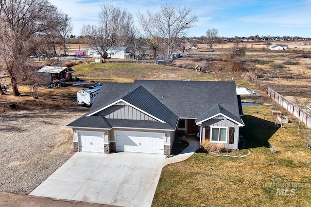 view of front facade featuring board and batten siding, concrete driveway, an attached garage, and fence