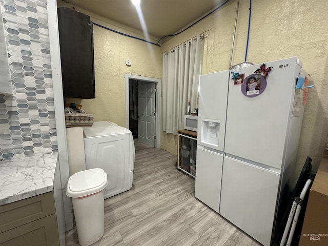 kitchen featuring light hardwood / wood-style floors, white appliances, and washer / dryer